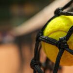Tennis ball in net, close up and space for text