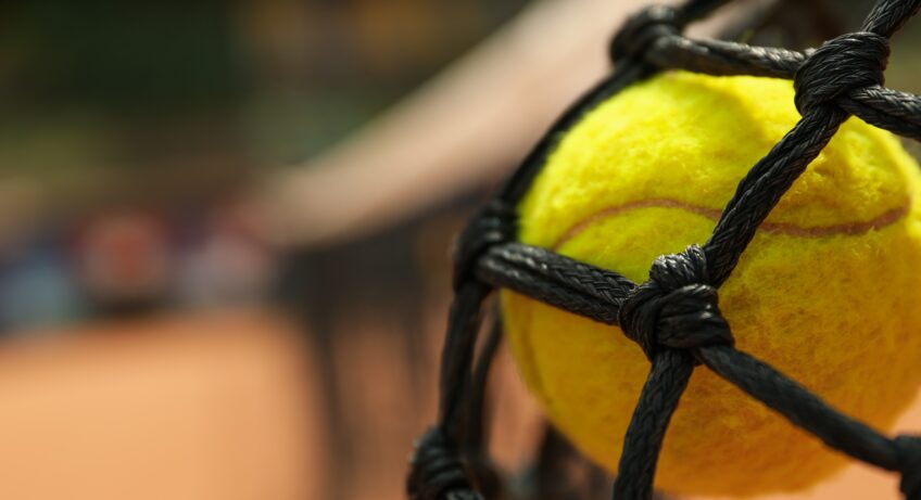 Tennis ball in net, close up and space for text