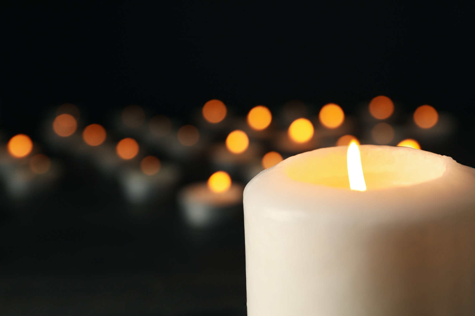 Burning candles on black background, space for text
